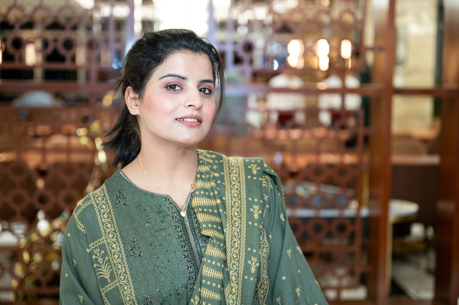 Elegant portrait of a woman in a green traditional dress indoors.